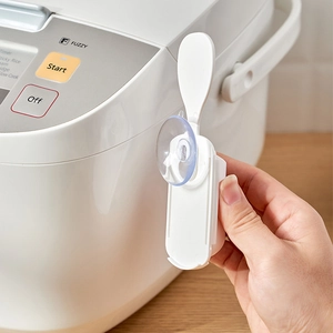 Japanese style suction cup rice spoon holder mounted on a white rice cooker surface
