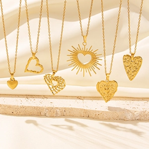 Six unique 18k gold plated heart necklaces displayed on an elegant beige stone base