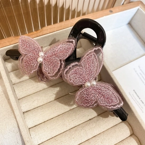 Detail of pink embroidered butterflies with faux pearls on a black lace hair claw clip