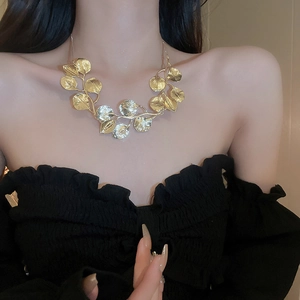 Close-up of golden leaf necklace on model showcasing the bold metallic design and style