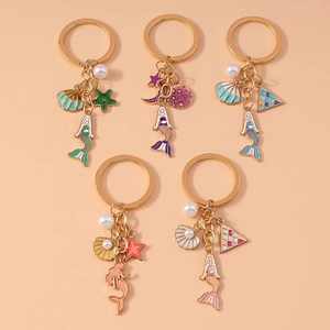 Detailed view of five mermaid keychains with colorful enamel, pearls, and starfish charms