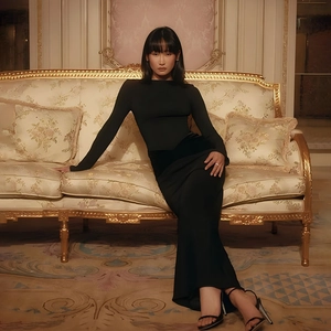 Detail view of a slim-fit black long-sleeve maxi dress on a vintage luxury sofa