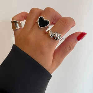 Detail of silver S925 heart rings and vintage knot band on a model hand with clear shadows