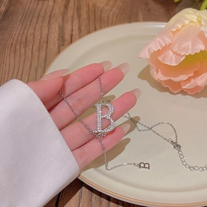 Detail of silver letter B pendant necklace with pavé zircons on a delicate chain