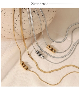Close-up of gold and silver layered snake chain necklaces on soft fabric background