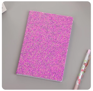 Close-up of pink purple sequin notebook cover with glitter texture and cherry pen