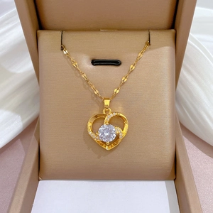 Elegant gold titanium heart necklace with central round crystal in a beige jewelry box