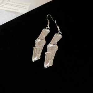 Macro shot of silver irregular twisted earrings with liquid metal texture on black velvet