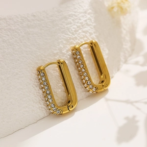 Elegant 18k gold plated U-shaped earrings with sparkling white zircons on stone background