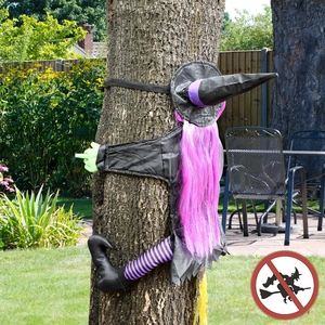 Detail of life-size crashing witch with purple hair tied to a tree for Halloween decor