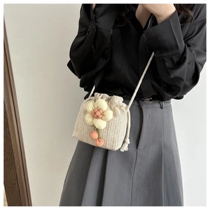 Mini borsa a secchiello in paglia con ciondolo floreale in un outfit dallo stile chic