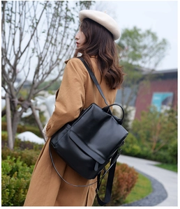 Close-up of black leather travel backpack with flap closure and adjustable straps