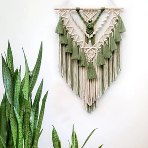 Detail of bohemian handmade woven tapestry with beige and green cotton tassels and wood pole