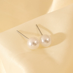 Classic white pearl earrings with stainless steel posts on elegant silk background