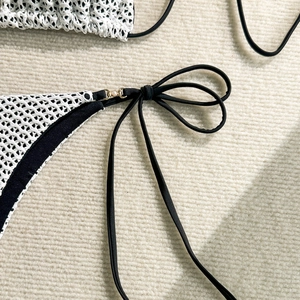 Detail of white crochet bikini bottom with black trim and elegant pearl gold ring charms