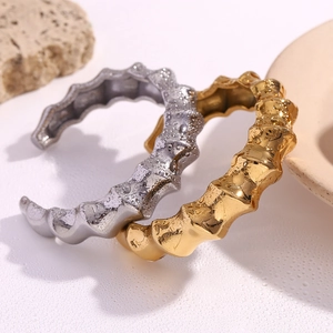 Detailed view of gold and silver spiral bamboo open bangles with water droplets on stone