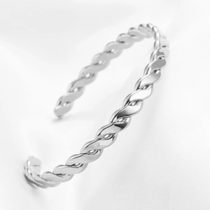 Close-up of silver C-shaped twisted rope cuff bracelet on white silk background
