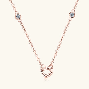 Detail of rose gold heart pendant necklace featuring sparkling circular zircon accents