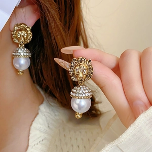 Detail of lion head earrings with sparkling rhinestones and elegant white pearls