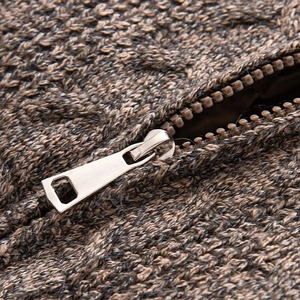 Close-up of the grey and dark brown chunky knit fabric with a silver metal zipper