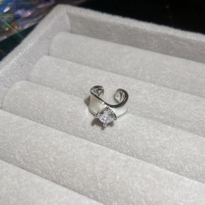 Close-up of silver ear cuff with white enamel detail and a sparkling zircon stone