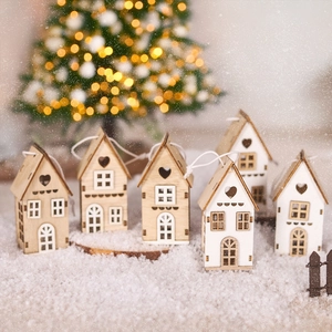 Miniature wooden Christmas houses with heart cutouts on snow with festive golden lights