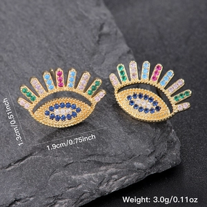 Golden evil eye earrings with colorful cubic zirconia stones on dark stone background
