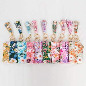 Flat lay of floral PU leather card holders with gold keychains and colorful tassels