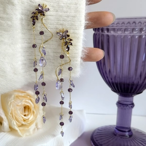 Detail view of sparkly purple butterfly and wisteria flower long tassel earrings