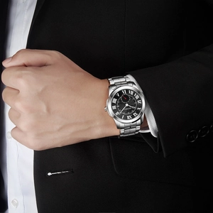 Men's silver stainless steel watch with black Roman numeral dial worn with a black suit
