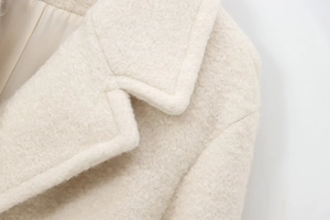 Detailed close-up of cream white wool texture and lapel design on the fashion overcoat