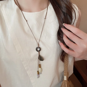 Detailed close-up of retro ethnic ceramic pendant necklace with beads on linen clothing