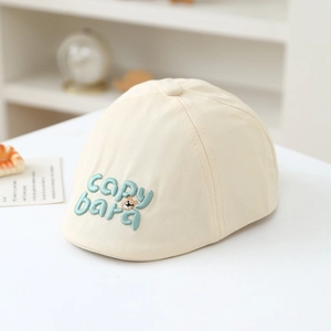 Close-up of beige cotton beret featuring green Capybara embroidery and bear letter details