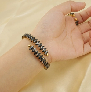 Detail of 18K gold-plated wrap bracelet and ring set with black marquise-cut zircons