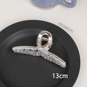 Detail view showing the 13cm iridescent laser hair claw clip on a stylish dark tray