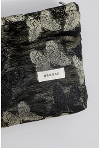 Detailed close-up of butterfly jacquard fabric and brand logo on a black cosmetic bag