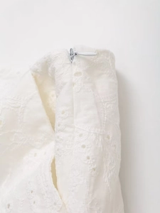 Macro shot of invisible zipper and intricate hollow embroidery on white blazer