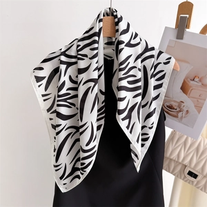 Detail of elegant black and white zebra print silk scarf hanging on a gold hanger