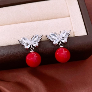 Close-up of butterfly pendant earrings with marquise crystals and red round bead drop