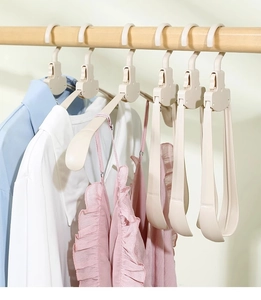 Detailed view of white foldable hangers on a wooden rod saving space for travel storage