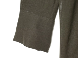 Close-up of the double-cuff stitching and fabric texture on dark olive green casual top