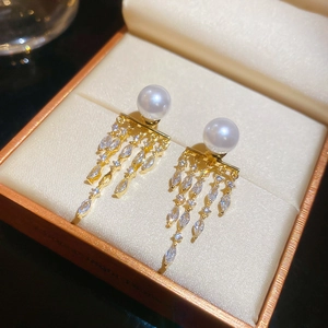 Detailed macro view of 14K gold plated tassel pearl earrings with sparkling zircon dangles