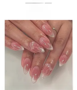 Détail d'ongles amande avec dégradé rose, nœud 3D, perle et paillettes argent