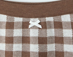 Detail of checkered knit shorts with white bow accent and elastic waistband texture