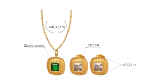 Detail of vintage gold jewelry set featuring green glass pendant and white zircon earrings