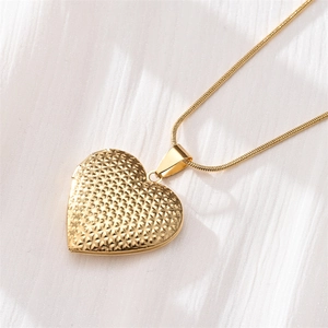 Detailed close-up of gold heart pendant with diamond-cut geometric texture on snake chain