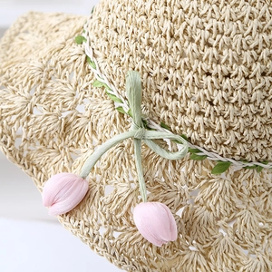Summer wide brim straw sun hat with green cord and pink tulip pendants on white background
