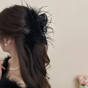Detail view of a black feather mesh rabbit ear hair claw on model's hair