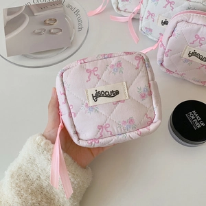 Quilted floral cotton makeup bag with pink ribbon and zipper closure held by hand