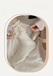 Detailed view of white cotton ribbed socks with delicate lace trim and ribbon bow